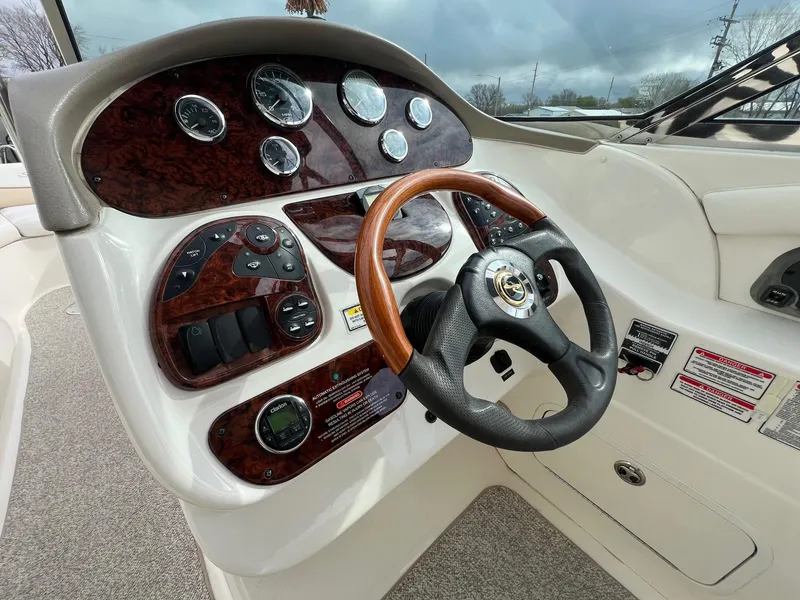 Slide: The Image of 2003 Sea Ray 290 Bowrider dashboard with wood accents and steering wheel. - 17