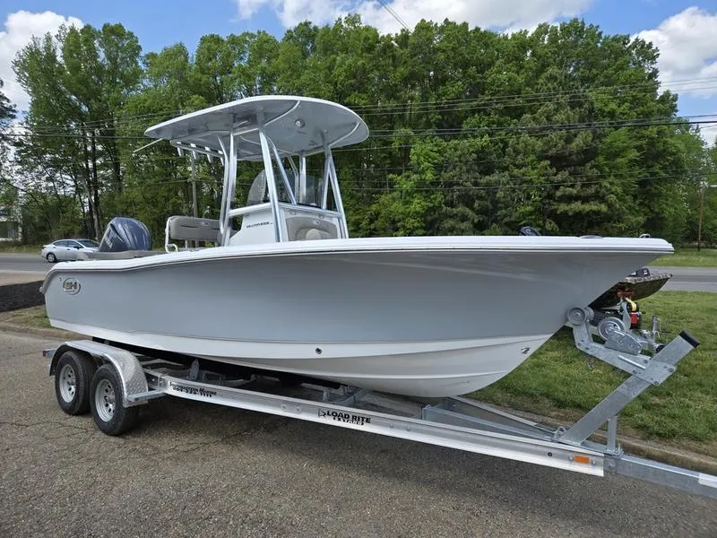 Slide: The Image of 2025 Sea Hunt Ultra 219 boat on trailer, parked outdoors with trees in background. - 0