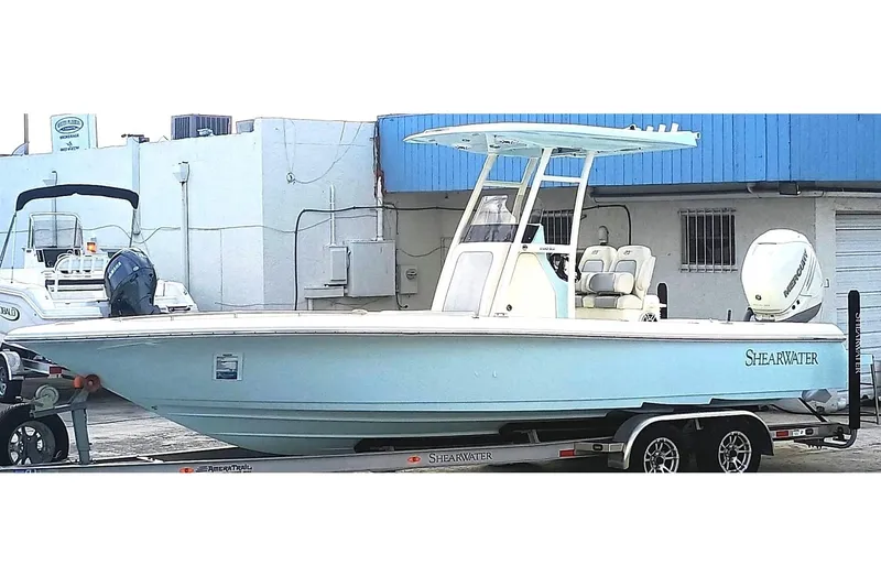 Slide: The Image of 2023 ShearWater 260 SS boat on trailer, light blue hull, parked outdoors. - 1