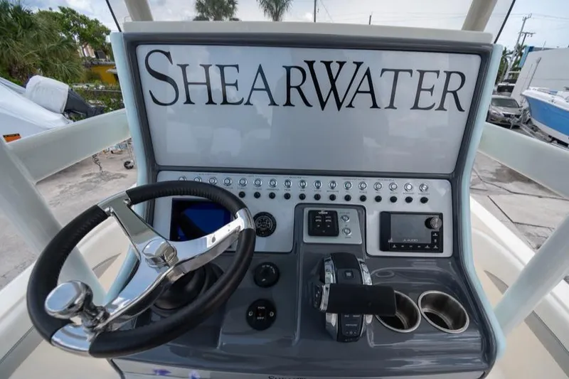 Slide: The Image of 2023 ShearWater 260 SS boat dashboard with steering wheel and controls. - 13