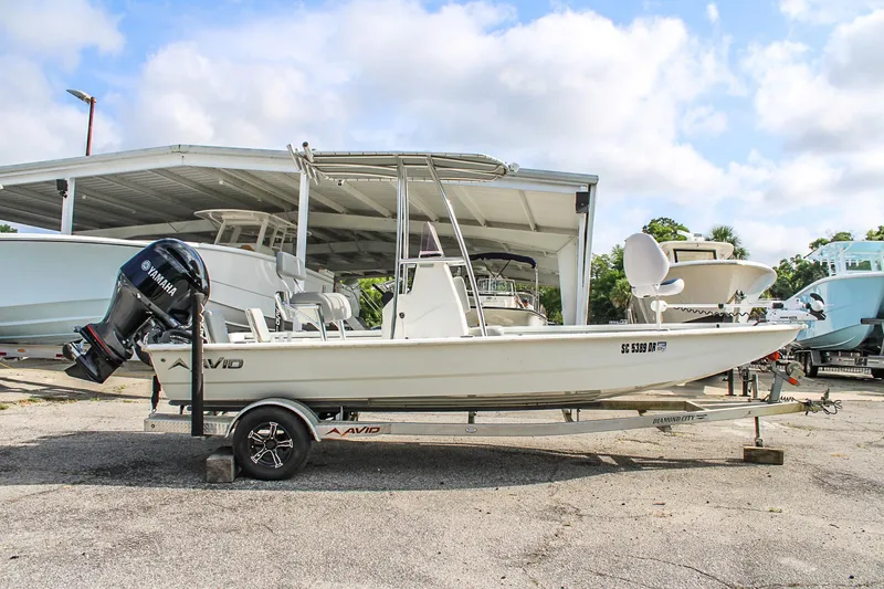 Slide: The Image of 2021 Avid 21 FS boat on trailer, parked outdoors under a partly cloudy sky. - 4