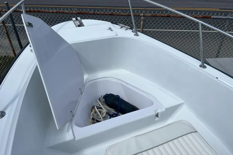 Slide: The Image of 1997 Boston Whaler Outrage 20 boat with open storage compartment and visible ropes. - 12