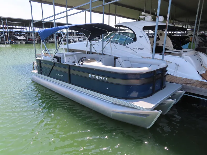 Slide: The Image of 2022 Crest Classic LX 220 pontoon boat docked in marina, featuring blue canopy and sleek design. - 4