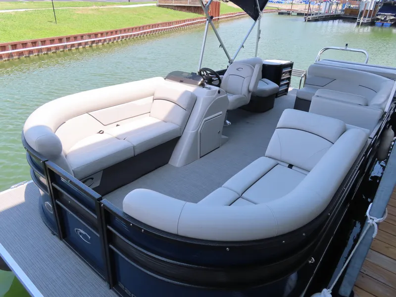 Slide: The Image of 2022 Crest Classic LX 220 pontoon boat with spacious seating on a calm lake. - 5
