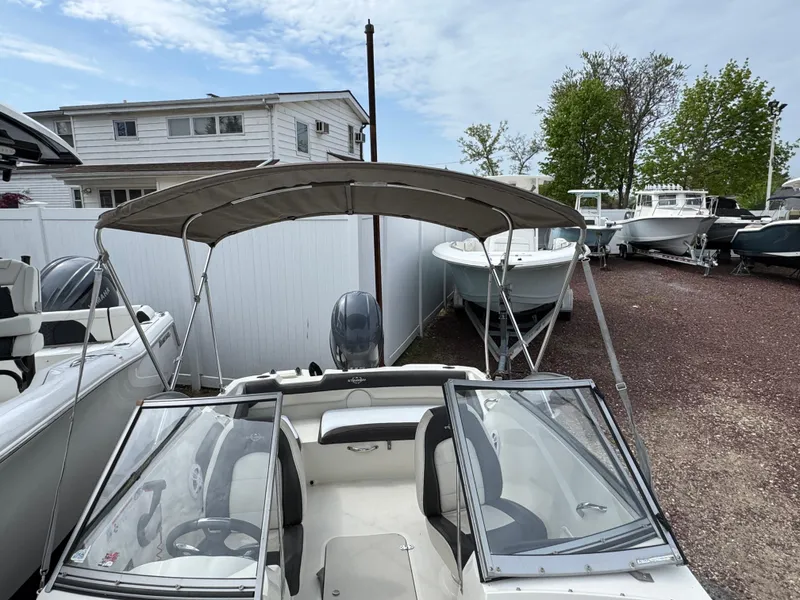Slide: The Image of 2019 Stingray 191 DC boat with canopy, parked outdoors near other boats. - 15