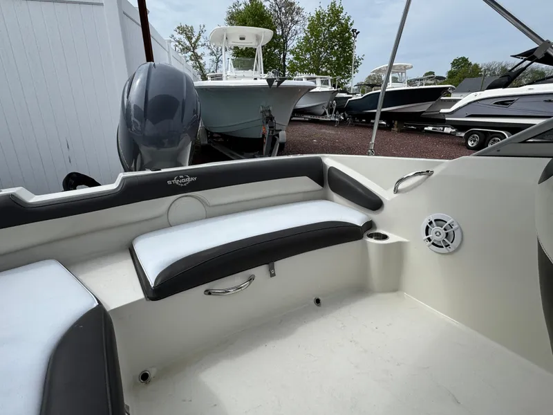 Slide: The Image of 2019 Stingray 191 DC boat interior with seating and motor, docked among other boats. - 17