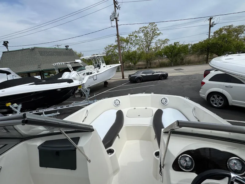 Slide: The Image of 2019 Stingray 191 DC boat interior view in a parking lot with cars and other boats. - 18