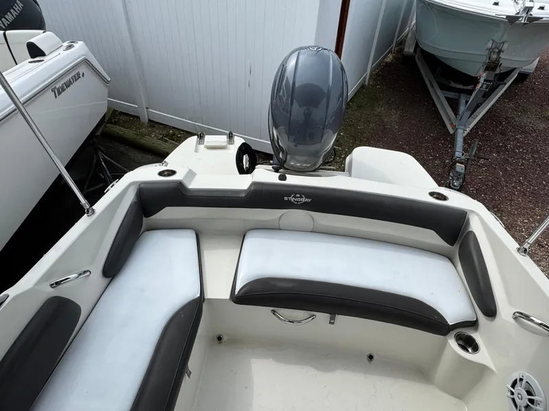 Slide: The Image of 2019 Stingray 191 DC boat interior with seating and motor, parked in a storage area. - 5