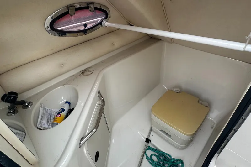 Slide: The Image of 2001 Sea Ray 240 Sundeck interior with compact bathroom and portable toilet. - 15