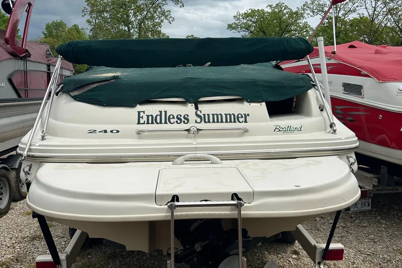 Slide: The Image of 2001 Sea Ray 240 Sundeck boat named "Endless Summer" with green cover, parked outdoors. - 28