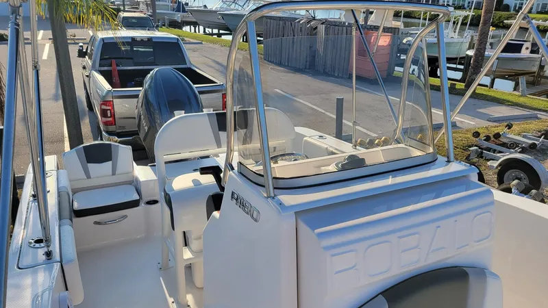Slide: The Image of 2024 Robalo R180 Center Console boat docked near a pickup truck. - 13