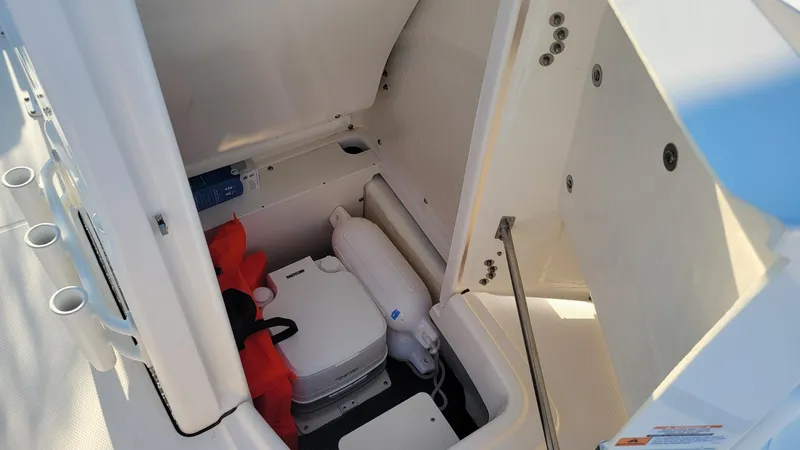 Slide: The Image of 2024 Robalo R180 Center Console storage area with safety equipment and portable toilet. - 15