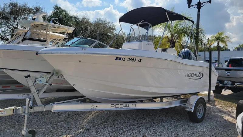 Slide: The Image of 2024 Robalo R180 Center Console boat on trailer, parked outdoors. - 2
