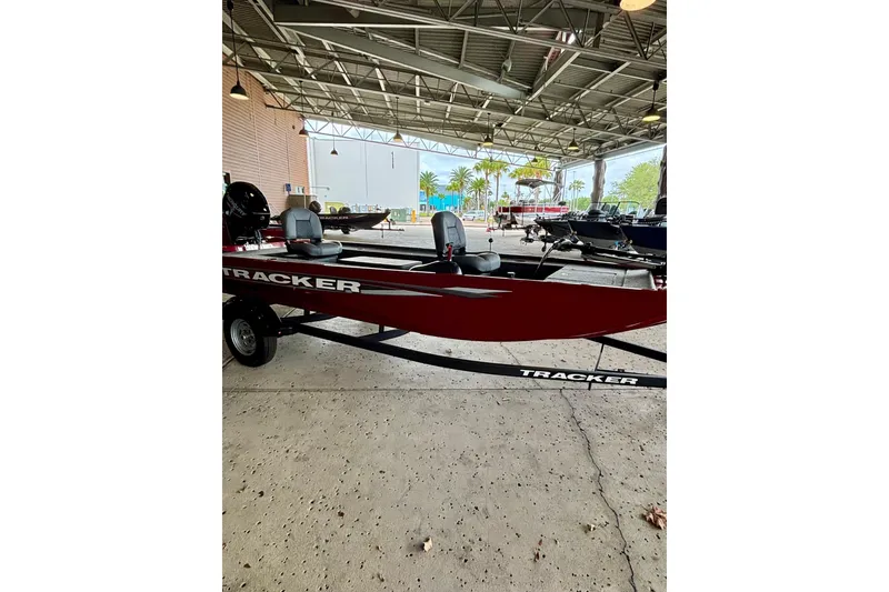 The Image of 2025 Tracker Panfish 17 boat in showroom, red exterior, under industrial lighting. - 0