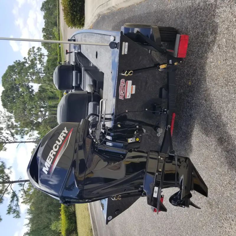 Slide: The Image of 2025 Tracker Panfish 17 boat with Mercury outboard motor, parked on pavement. - 2
