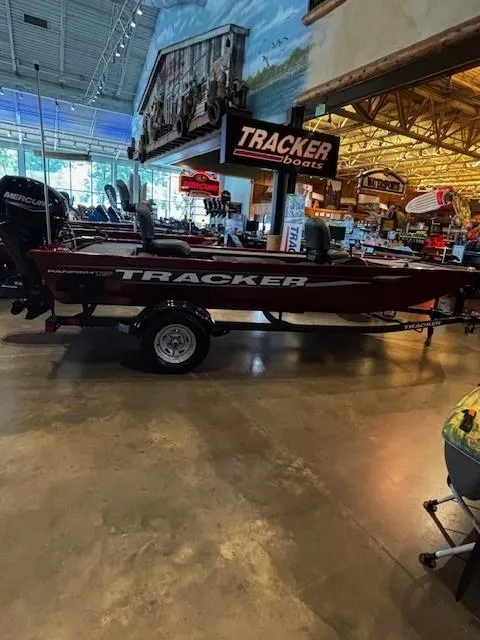 The Image of 2025 Tracker Panfish 17 boat displayed indoors at a showroom with various boating equipment. - 0