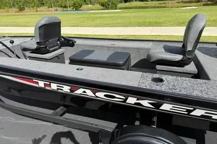 Slide: The Image of 2025 Tracker Panfish 17 boat interior with seating and storage, parked outdoors. - 3