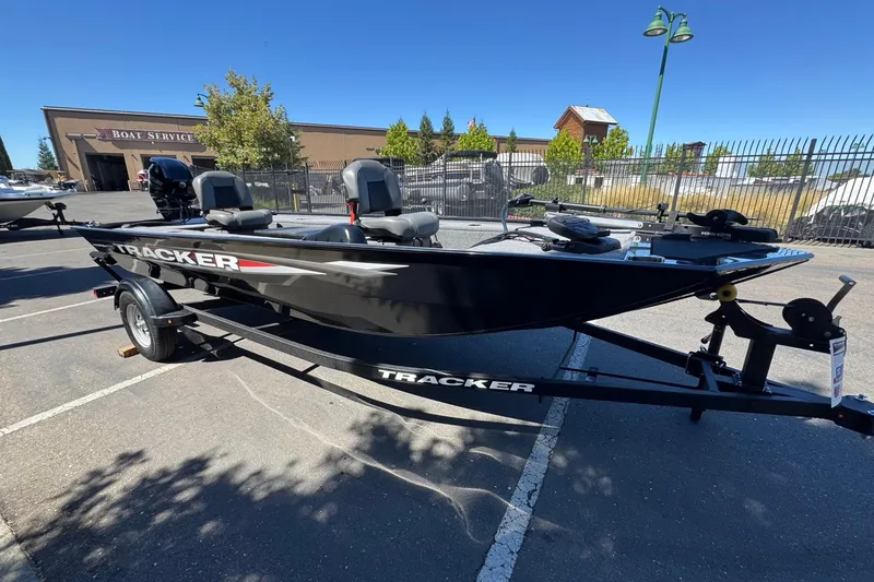 Slide: The Image of 2025 Tracker Panfish 17 boat on trailer in parking lot, near boat service building. - 6