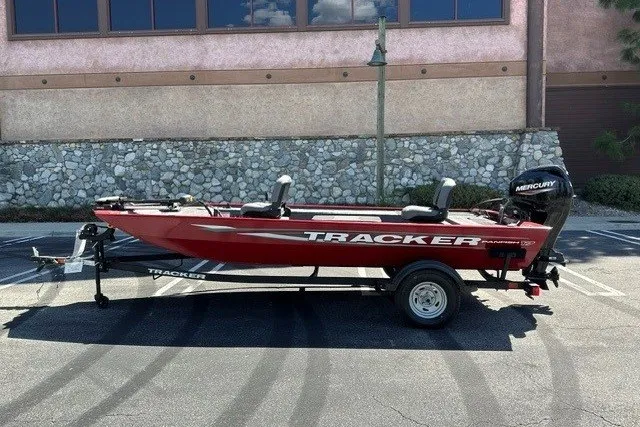 Slide: The Image of 2025 Tracker Panfish 17 boat in red, parked on a trailer in a lot. - 49