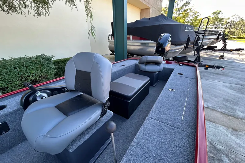 Slide: The Image of 2025 Tracker Panfish 17 boat interior with seating and motor, parked outdoors. - 3