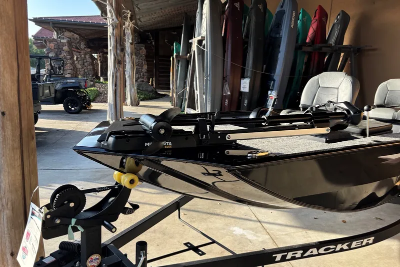 Slide: The Image of 2025 Tracker Panfish 17 boat on trailer, parked near outdoor gear. - 8
