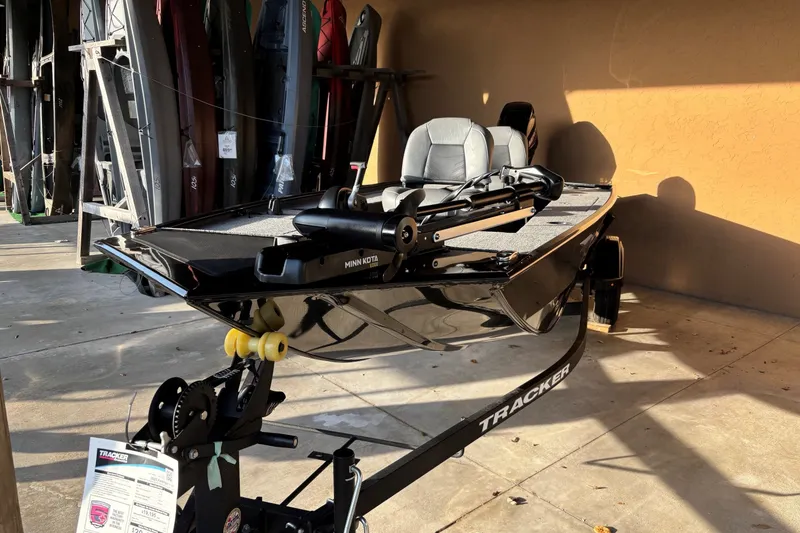 Slide: The Image of 2025 Tracker Panfish 17 boat on trailer, displayed in a showroom with kayaks. - 7