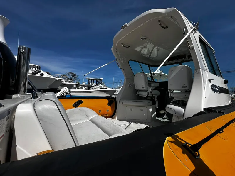 Slide: The Image of 2013 Protector Targa 30 boat interior with white and yellow seating under clear blue sky. - 4