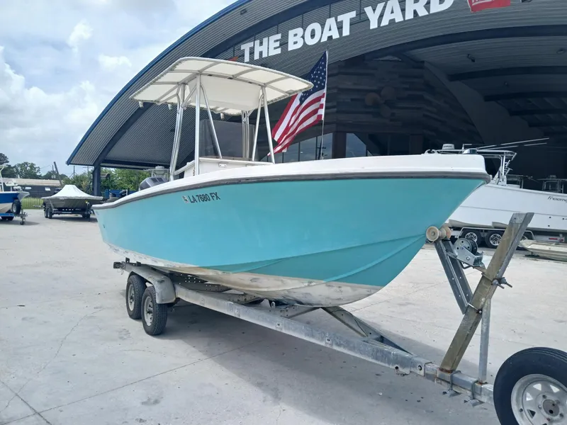 Slide: The Image of 1980 Mako 213 boat on trailer at The Boat Yard, featuring a blue hull and American flag. - 1