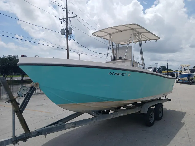 Slide: The Image of 1980 Mako 213 boat on trailer, light blue hull, parked outdoors under cloudy sky. - 2