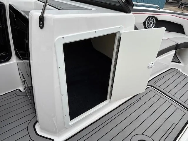 Slide: The Image of 2018 Yamaha Boats 212X interior storage compartment with open door, showcasing sleek design. - 15