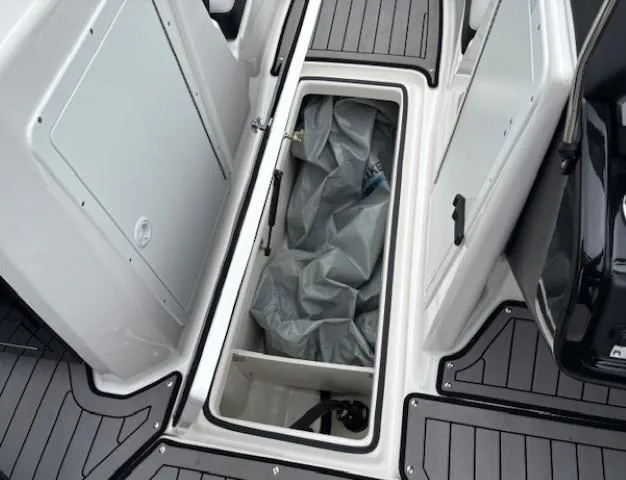 Slide: The Image of 2018 Yamaha Boats 212X storage compartment with gray flooring and open hatch. - 17