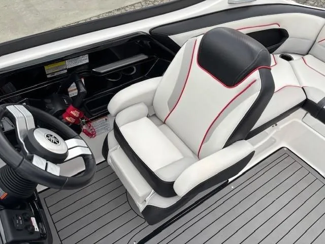 Slide: The Image of 2018 Yamaha Boats 212X interior with sleek white and black seating, red accents, and modern steering. - 25