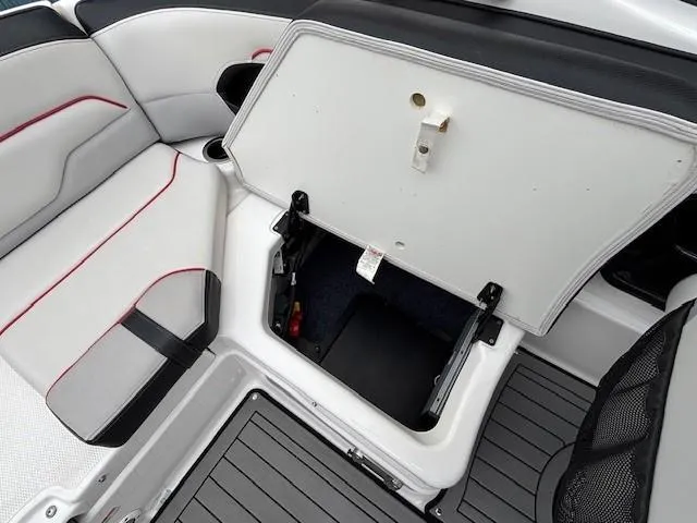 Slide: The Image of 2018 Yamaha Boats 212X interior storage compartment with open hatch, showcasing seating and flooring. - 31
