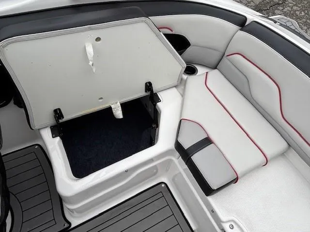 Slide: The Image of 2018 Yamaha Boats 212X interior storage compartment with cushioned seating and sleek design. - 32
