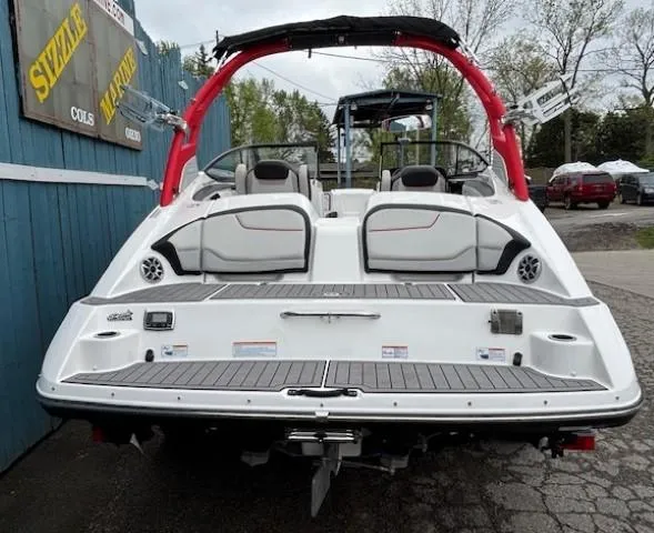 Slide: The Image of 2018 Yamaha Boats 212X with red accents, rear view at a marina. - 4