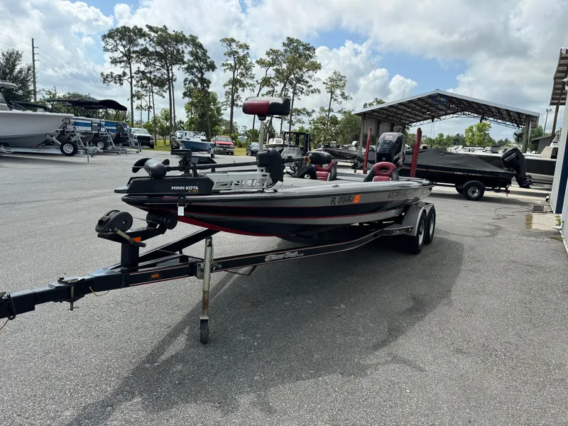 Slide: The Image of 2013 Blazer 625 boat on trailer in outdoor lot, surrounded by trees and other boats. - 3