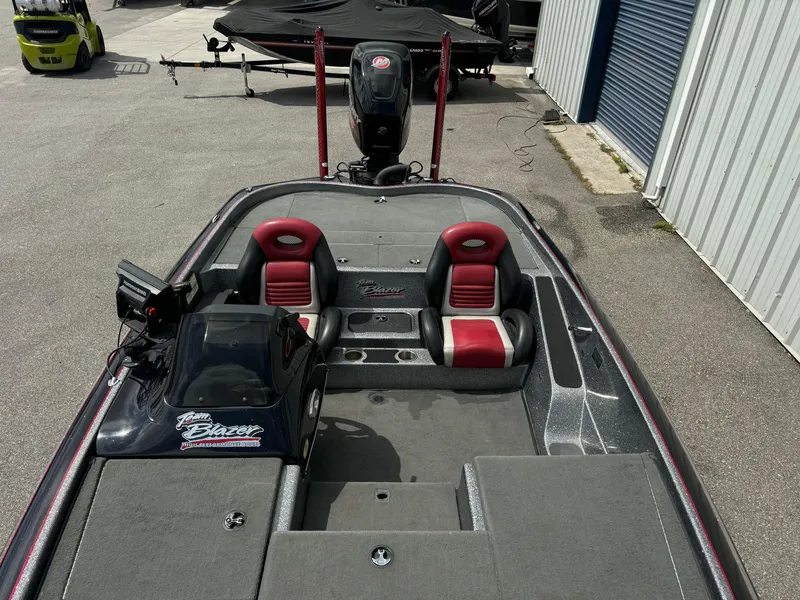 Slide: The Image of 2013 Blazer 625 boat with red seats and motor, parked near a building. - 9