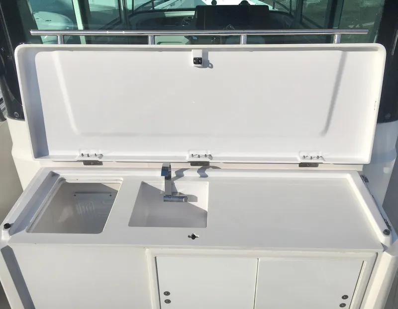 Slide: The Image of 2019 Axopar 28 CABIN boat sink and storage area with open lid. - 14