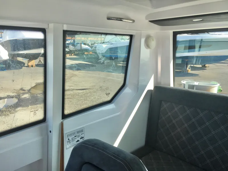 Slide: The Image of Interior view of 2019 Axopar 28 CABIN boat with cushioned seating and large windows. - 34