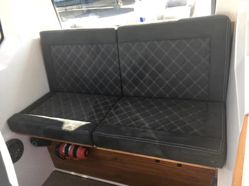 Slide: The Image of 2019 Axopar 28 CABIN interior with black cushioned seating and fire extinguisher. - 37