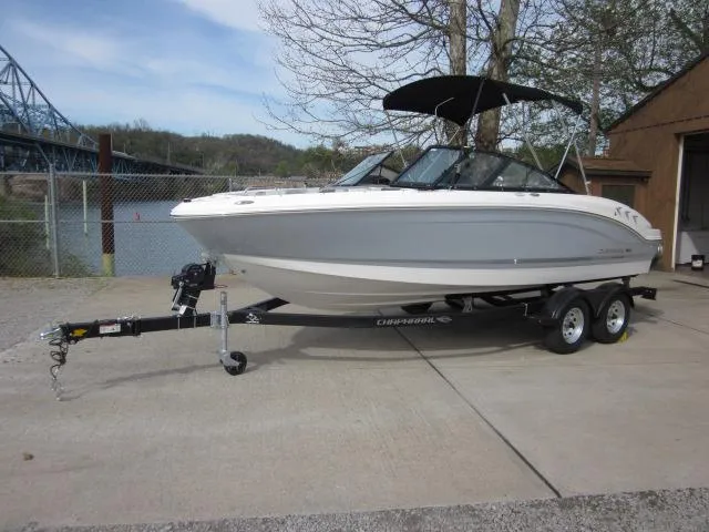 Slide: The Image of 2025 Chaparral 21 SSi boat on trailer, parked outdoors near a fence and trees. - 3