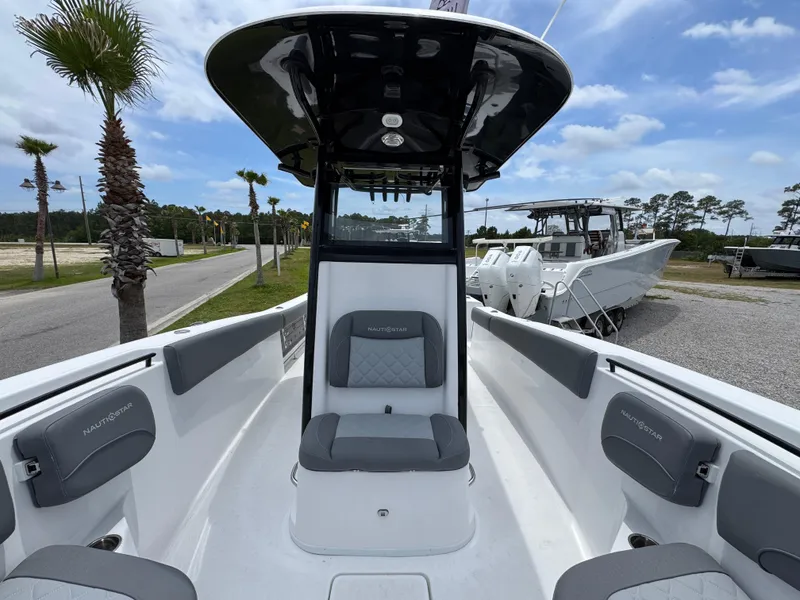 Slide: The Image of 2025 NauticStar 292 Legacy boat with seating, palm trees, and blue sky background. - 14