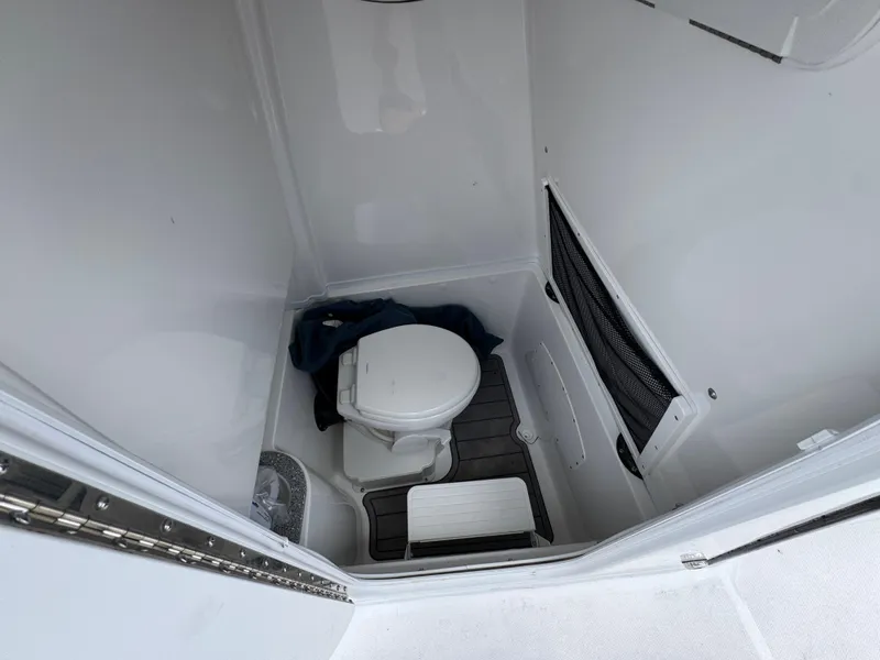 Slide: The Image of 2025 NauticStar 292 Legacy boat bathroom interior with toilet and storage net. - 17