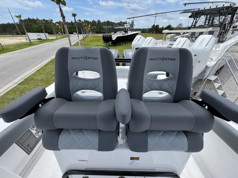 Slide: The Image of 2025 NauticStar 292 Legacy boat seats, gray upholstery, outdoor setting. - 19
