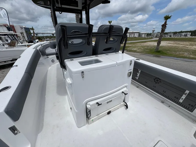 Slide: The Image of 2025 NauticStar 292 Legacy boat interior with seating and storage, under a cloudy sky. - 23