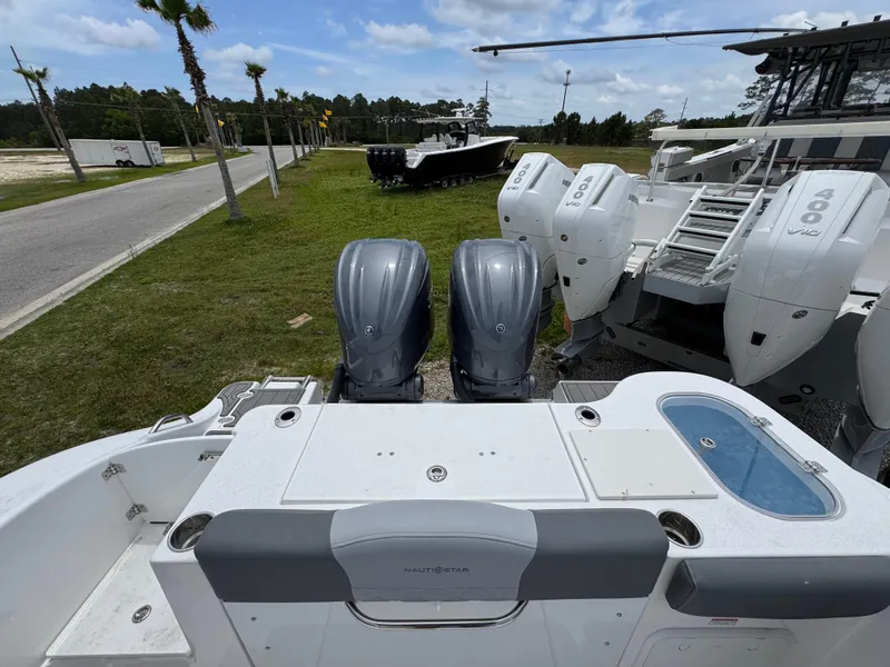 Slide: The Image of 2025 NauticStar 292 Legacy boat with dual outboard engines, docked on grass. - 27