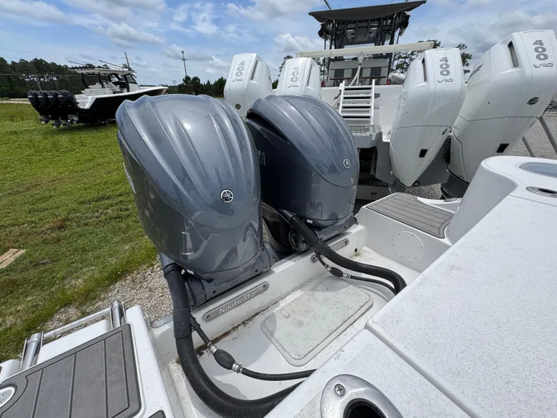Slide: The Image of 2025 NauticStar 292 Legacy boat with dual outboard engines, parked on grass. - 28