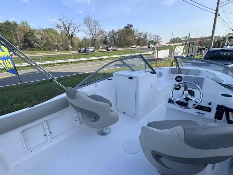 Slide: The Image of 2023 Key West 203 DFS boat interior with steering wheel and seating, parked near a road. - 17