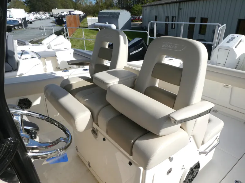 Slide: The Image of 2025 Boston Whaler 330 Outrage boat interior with dual cushioned seats and steering wheel. - 11