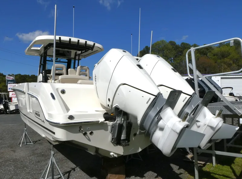 Slide: The Image of 2025 Boston Whaler 330 Outrage boat with dual engines, parked outdoors under clear sky. - 2